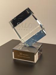 Статуэтка из оптического стекла в форме куба, поставленная на один из ее углов на постаменте.  Основание сувенира может быть выполнено из стекла, металла, дерева, камня по вашему желанию. С помощью различных техник гравировки, можно нанести практически любое изображение или надпись.  Подобная форма идеально подойдет для любого мероприятия, а также в качестве индивидуальной награды или предмета корпоративного стиля. 